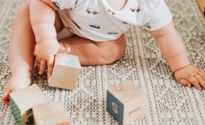 bebe com brinquedos de madeira
